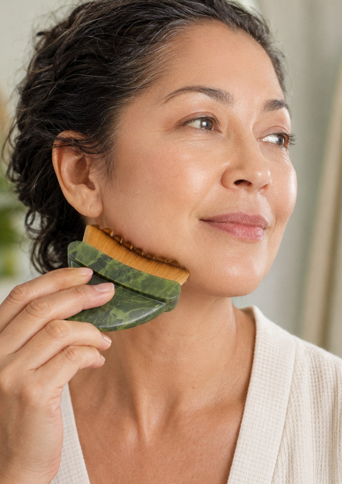 Woman using the Gua Sha Dry Brush along her jawline